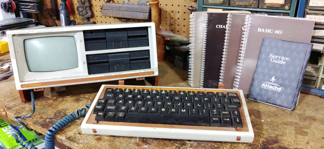 The Otrona Attache portable computer sits on my workbench, with a beige housing, small 5 inch CRT and detachable keyboard. Also featured are some software manuals I recieved with the unit from the original owner