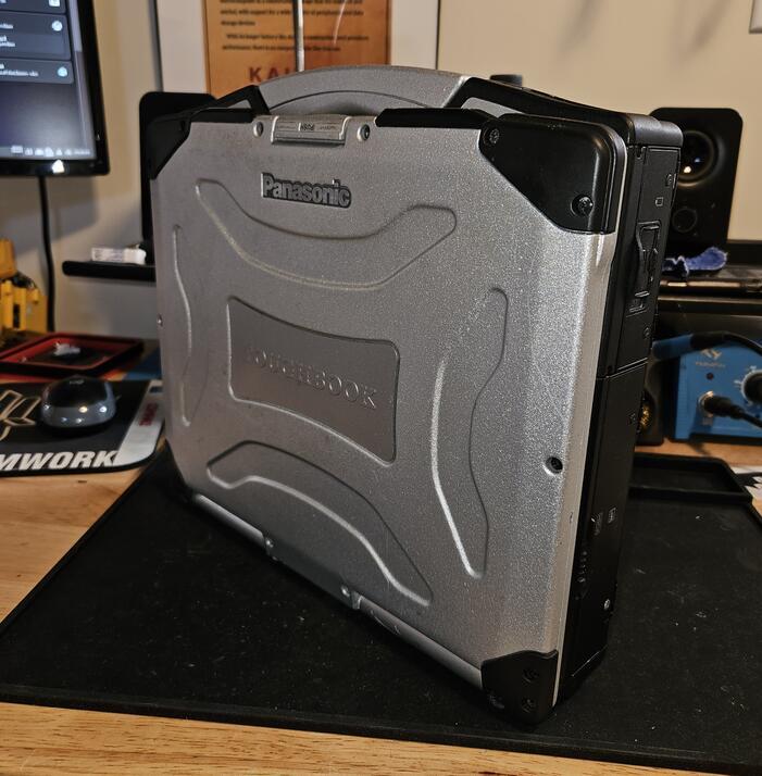 A Panasonic Toughbook model CF-29 with the lid closed to show the rugged exterior, sitting on a workbench